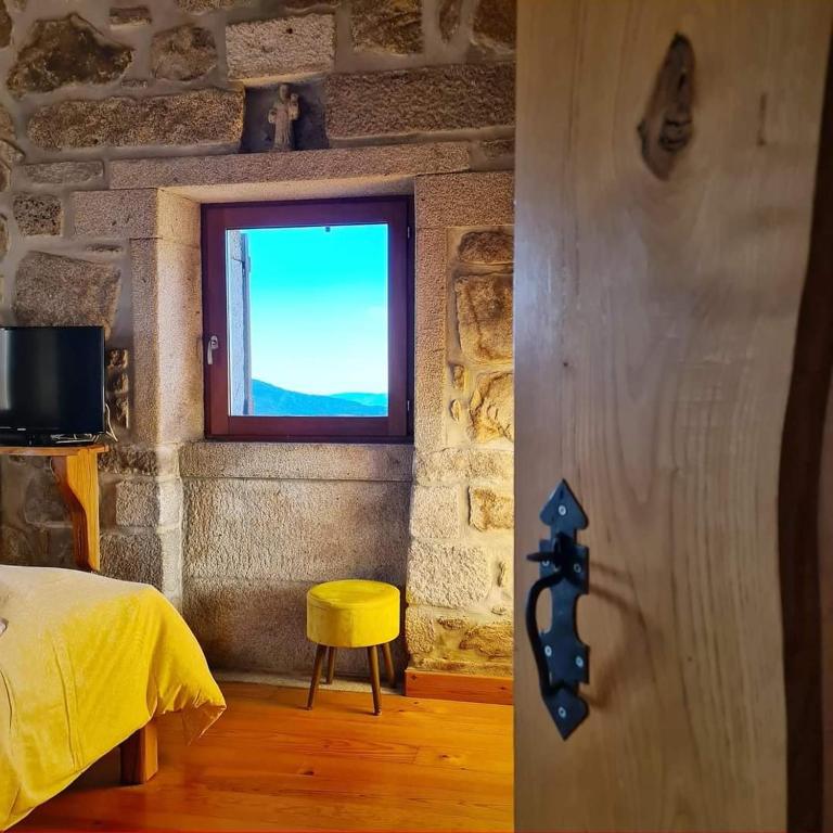 a bedroom with a window and a yellow stool at Cardenha da Bessada in Branda de Santo António