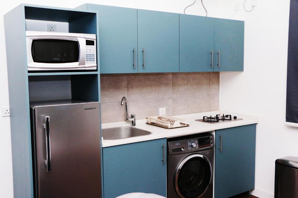 a kitchen with blue cabinets and a microwave and a dishwasher at Mandaren Suites in Taif