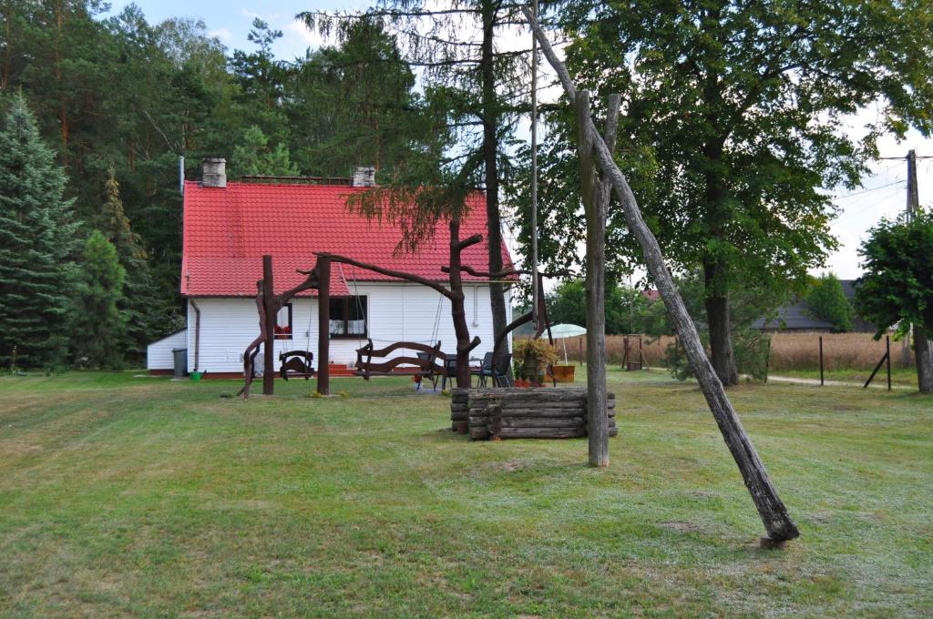 une aire de jeux en face d'une maison avec un toit rouge dans l'établissement Agroturystyka "Leśne Zacisze na Podlasiu", à Tuczna