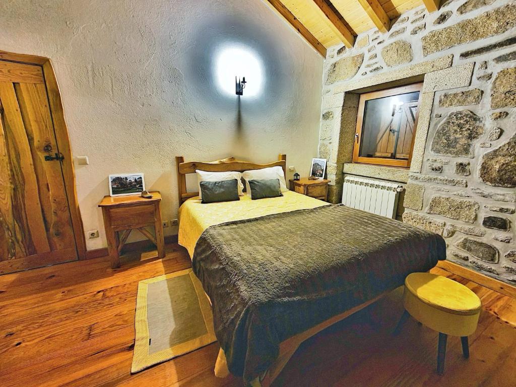 um quarto com uma cama e uma parede de pedra em Cardenha da Bessada em Branda de Santo António