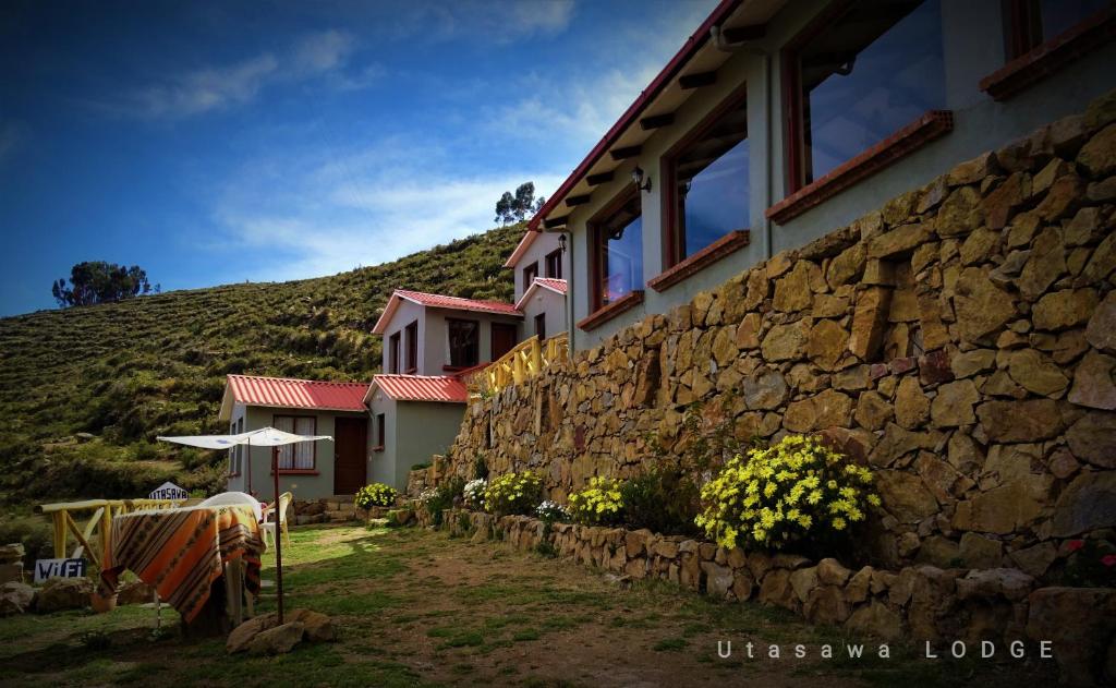 budynek z kamienną ścianą obok góry w obiekcie Utasawa w mieście Comunidad Yumani