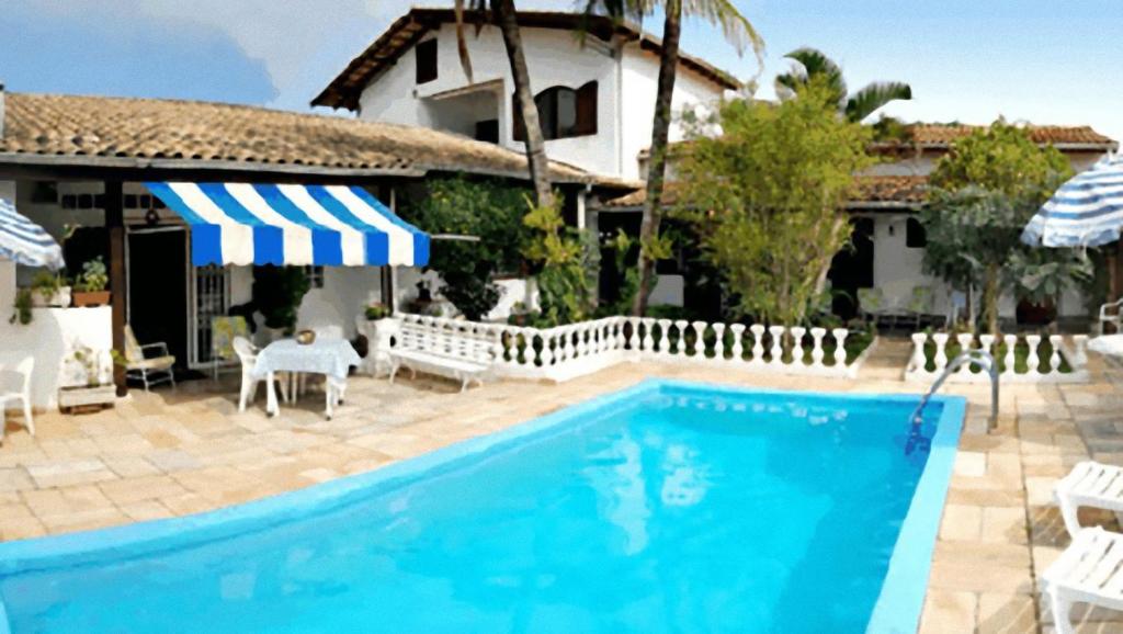 a swimming pool in front of a house at Hotel Pousada do Comendador in Guarujá