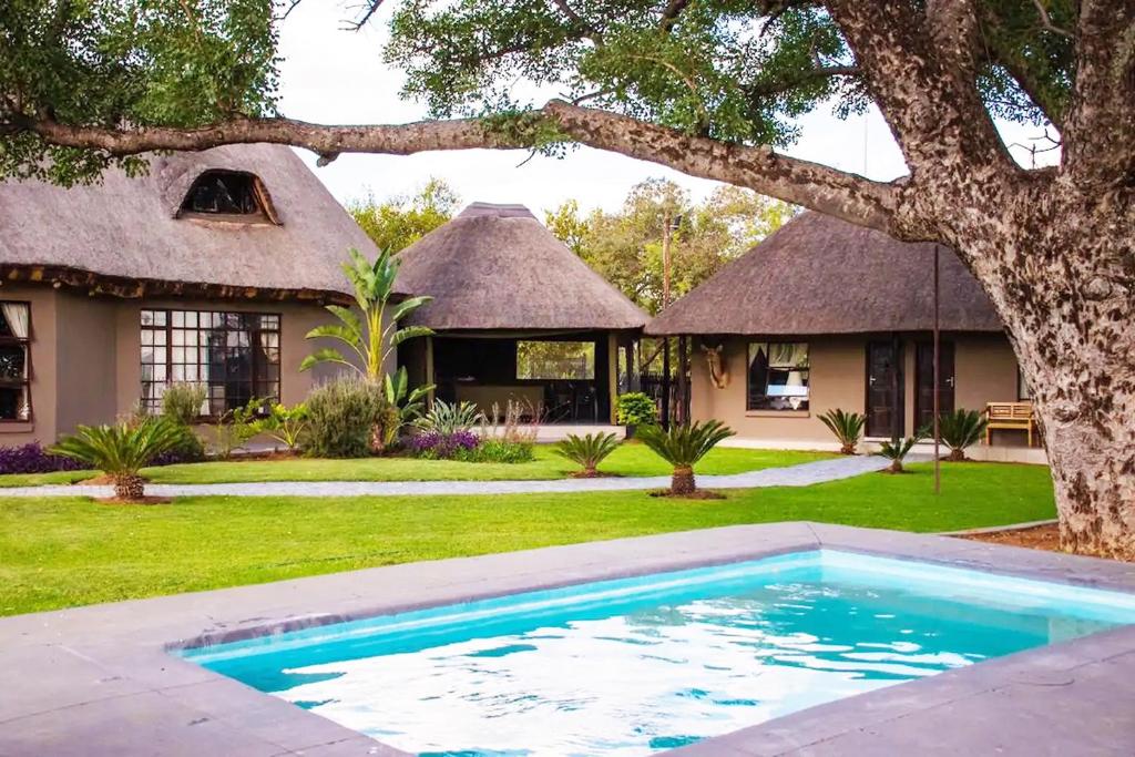 a house with a swimming pool in front of a yard at Sasavona Game Lodge in Warmbaths