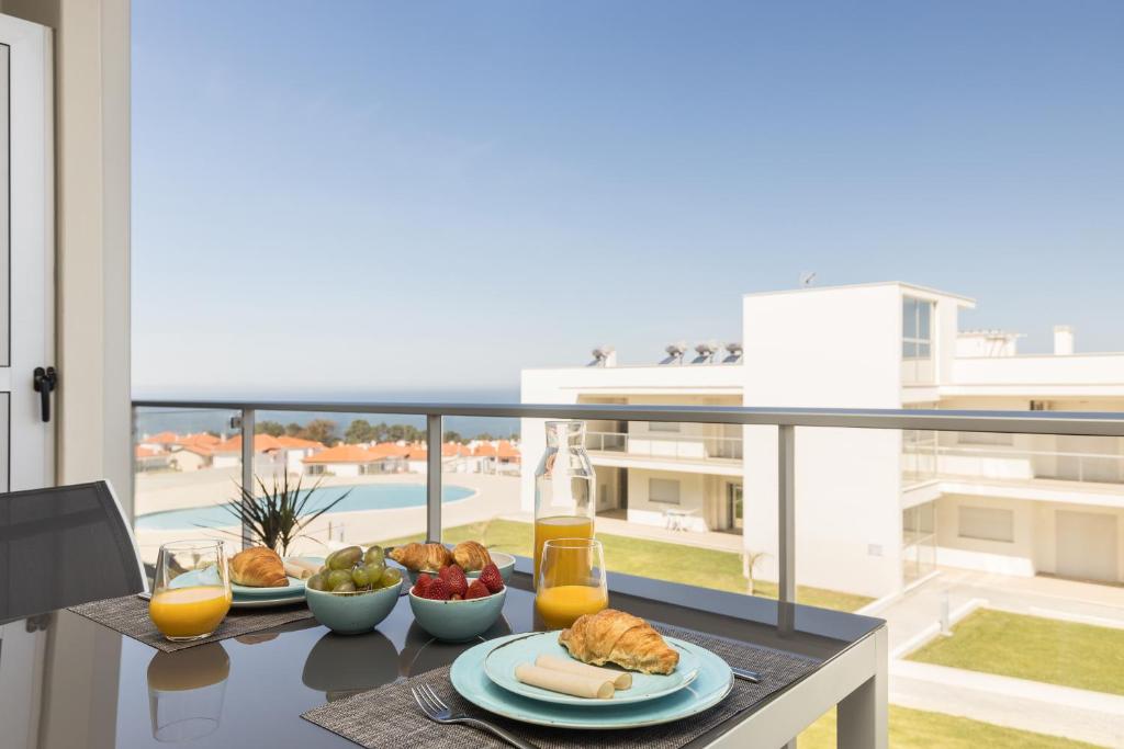 uma mesa com comida em cima de uma varanda em NazOndas Ap em Nazaré