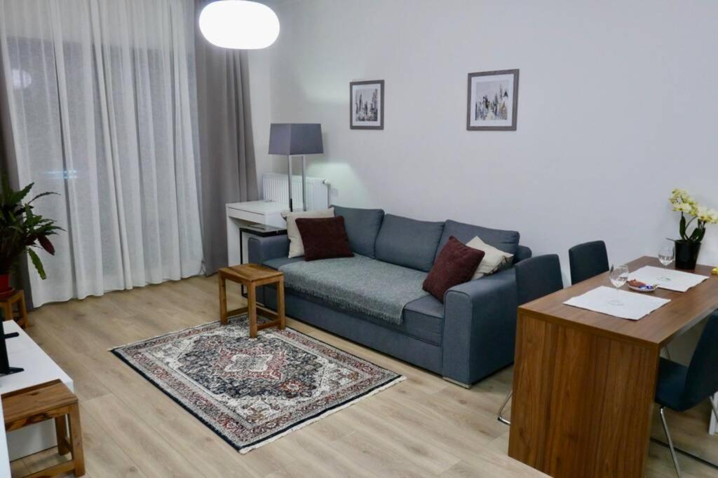 een woonkamer met een blauwe bank en een tafel bij Sarmacka Apartment in Wilanów in Warschau