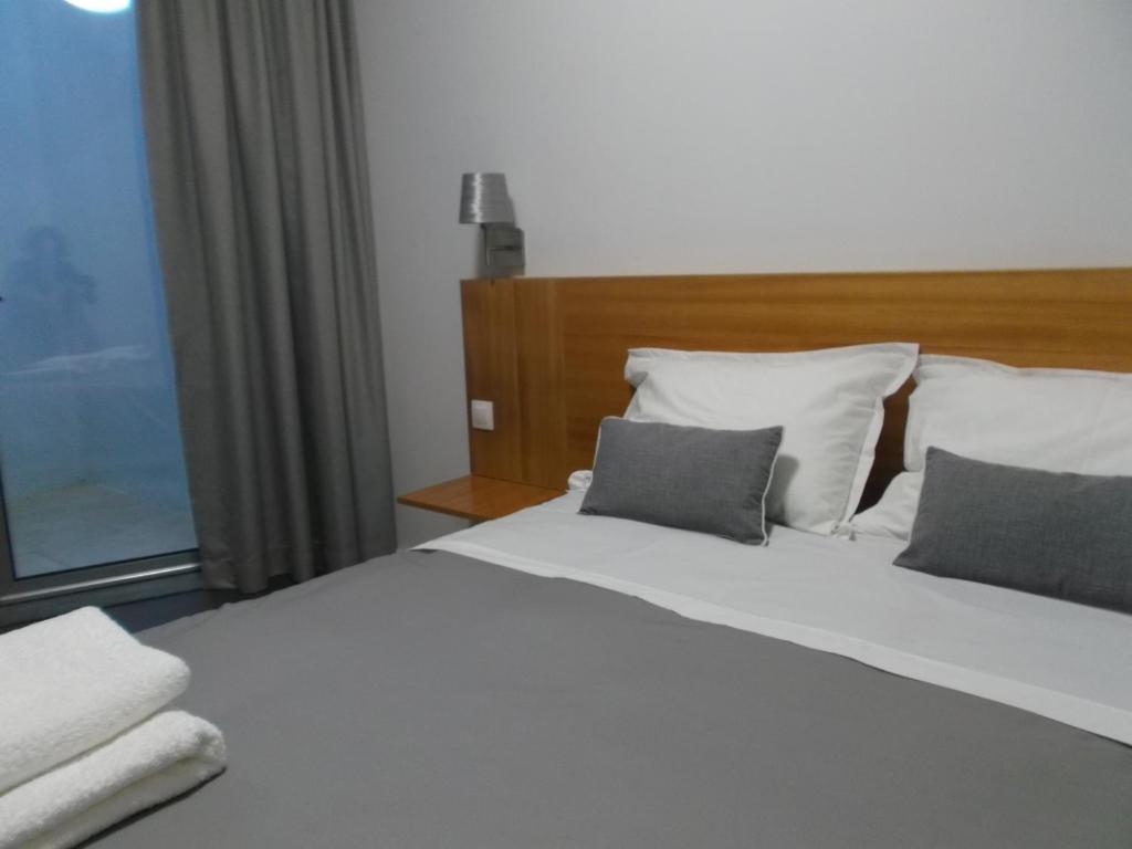 una camera con un letto bianco con due cuscini di Angra Downtown ad Angra do Heroísmo