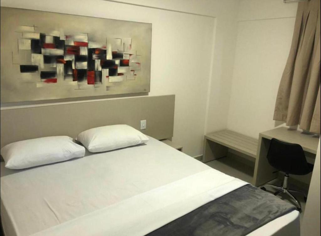 a bedroom with a bed with two pillows and a painting at Evian Thermas Residence - Caldas Novas in Caldas Novas