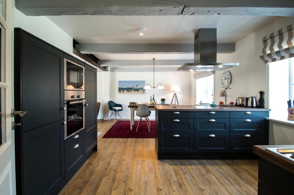 a kitchen with black cabinets and a dining room at Reethus Glücklicher Matthias Hausteil Waasterlun in Oldsum