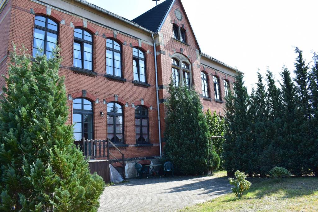 Kirchberg的住宿－Pension zur Alten Schule，前面有树木的大型砖砌建筑