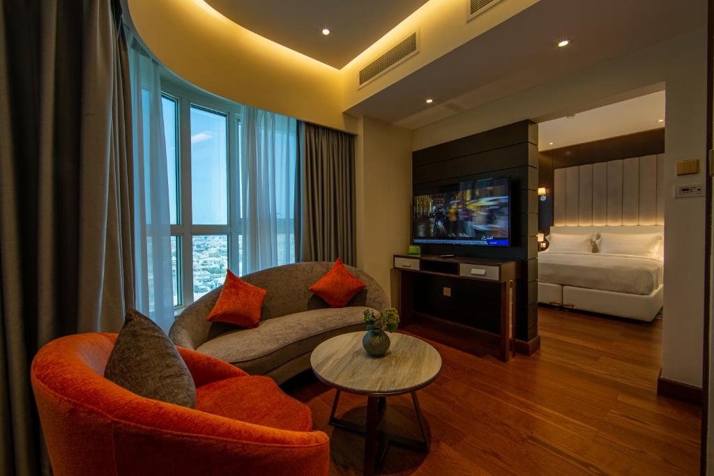 ein Wohnzimmer mit einem Sofa, einem TV und einem Bett in der Unterkunft Number One Tower Suites in Dubai