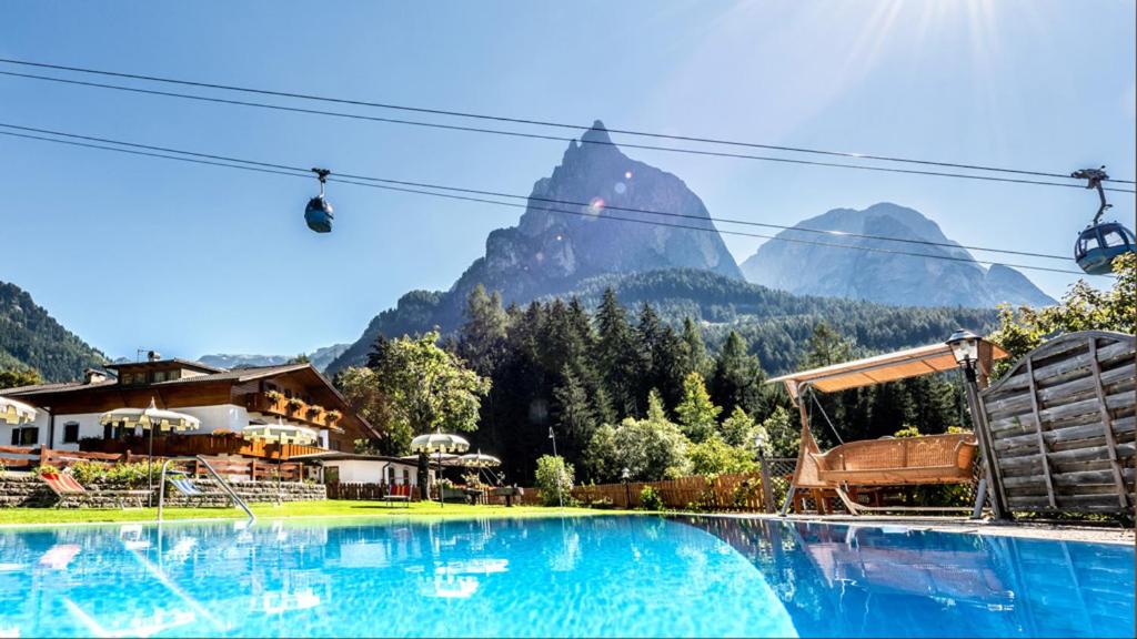 a large swimming pool with a mountain in the background at Hotel Profanter in Siusi