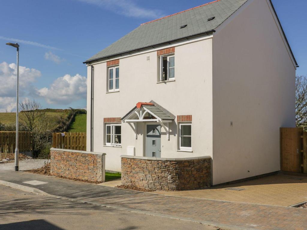 uma casa branca com uma parede de pedra à volta. em Trevena em Tintagel