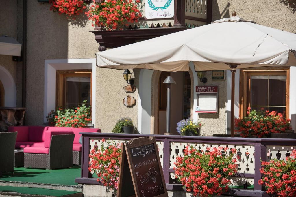 a patio with an umbrella and chairs and flowers at Hotel Livigno in Livigno