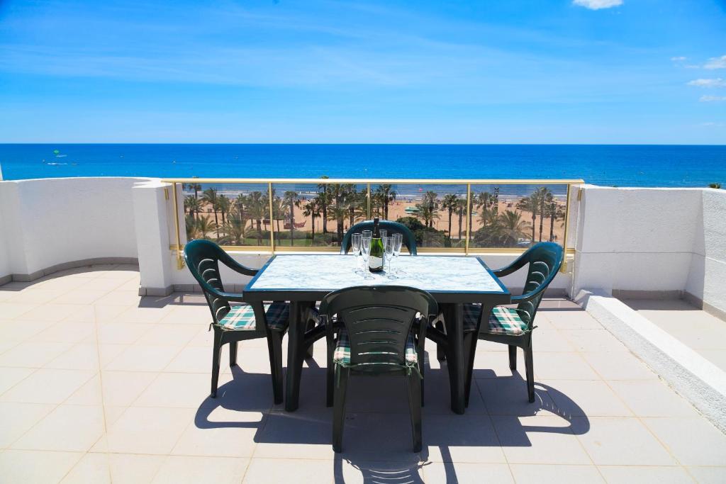 una mesa y sillas en un balcón con vistas al océano en UHC ACACIAS APARTMENTS SALOU, en Salou