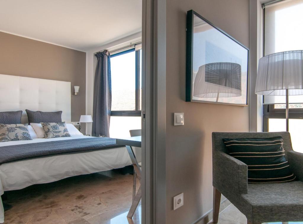 sypialnia z łóżkiem, krzesłem i oknami w obiekcie Picasso Suites 5.1 Paseo de Gracia w Barcelonie