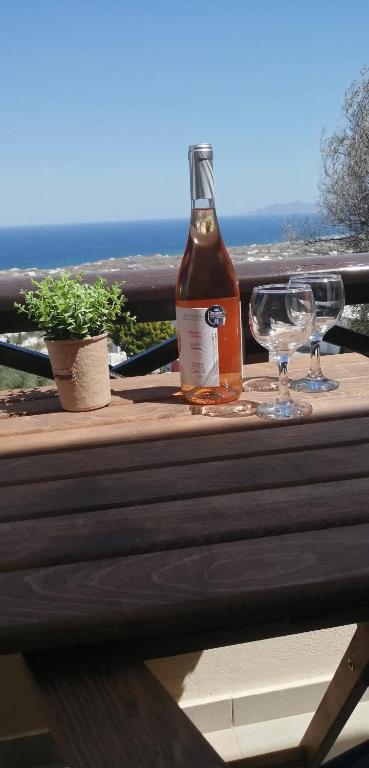 a bottle of wine and two glasses on a wooden table at Santo Spiti sou 3 in Fira