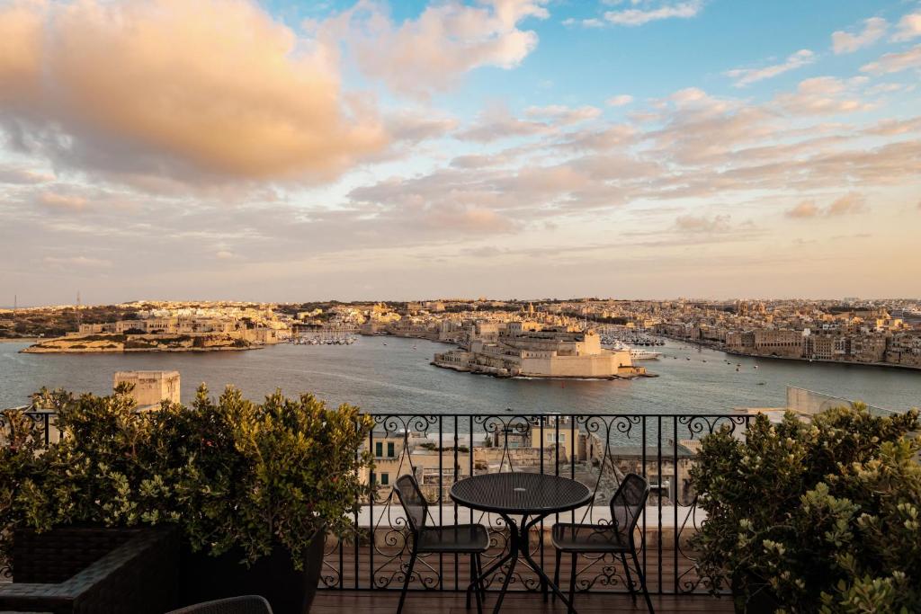 a balcony with a table and chairs and a view of a river at 1926 Le Parisot Boutique Suites in Valletta