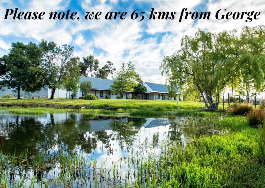 a house next to a pond with the words please note we are km km from at Shanzeley Guest House in George