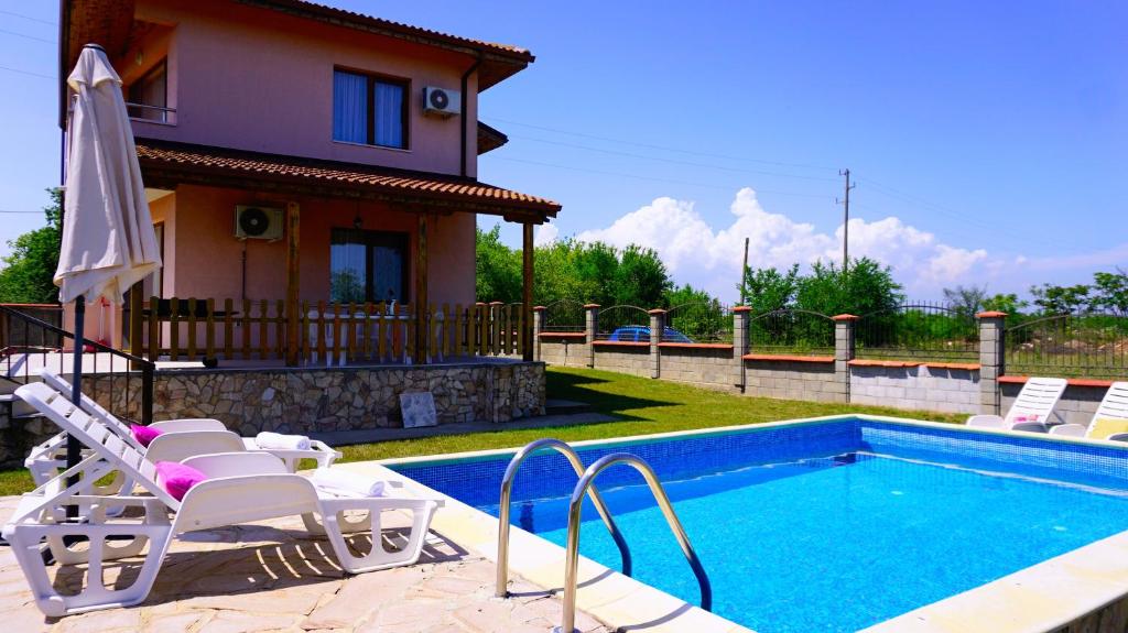 a swimming pool with chairs and a house at Вила Марна - Villa Marna in Bŭlgarevo