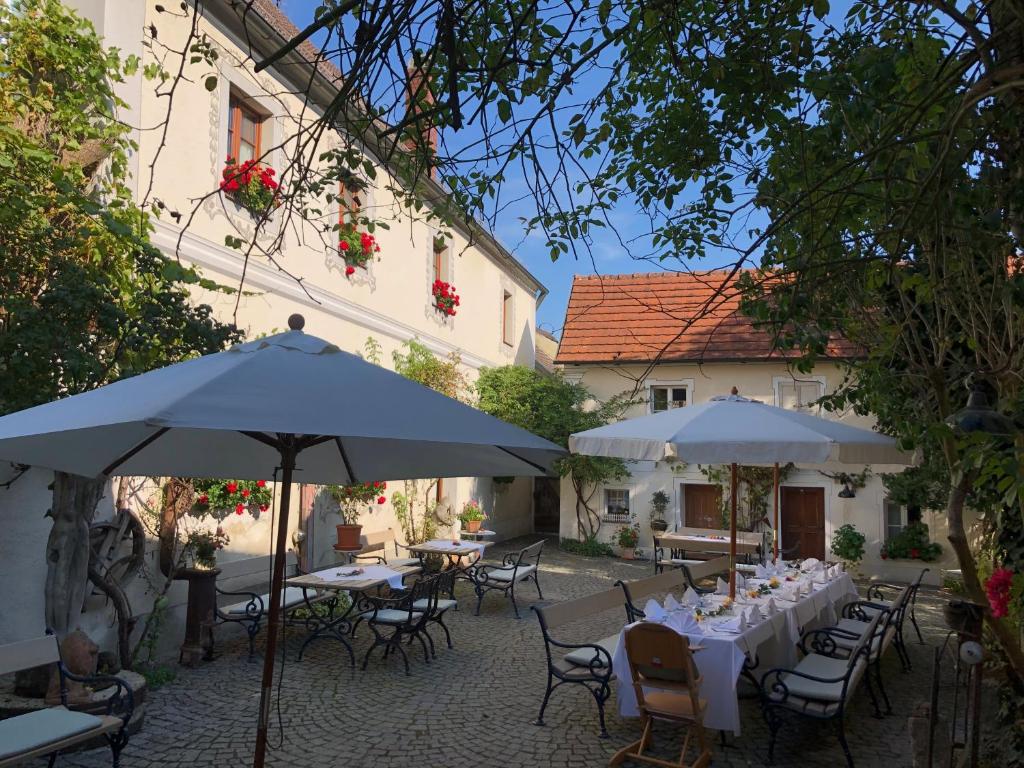 un patio extérieur avec des tables, des chaises et des parasols dans l'établissement CALLM aka Zum goldenen Löwen - zu Nacht bei der Destillerie, à Kallmünz