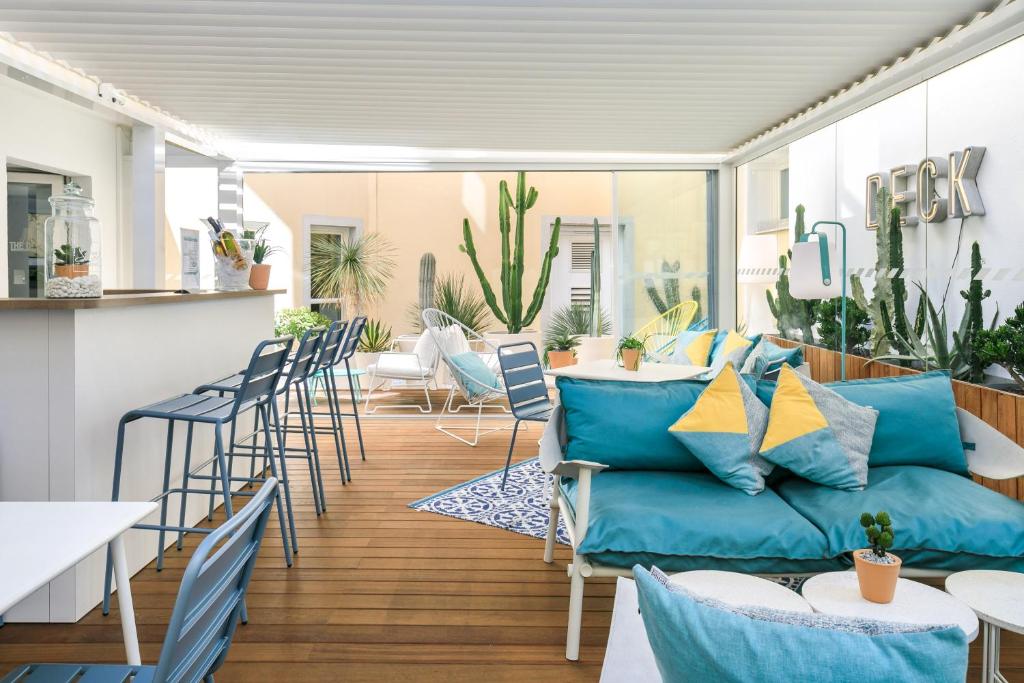 ein Wohnzimmer mit einem Sofa, Tischen und Stühlen in der Unterkunft The Deck Hotel by Happyculture in Nizza