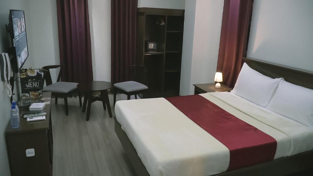 ein Hotelzimmer mit einem Bett, einem Tisch und Stühlen in der Unterkunft A.M @ 93rd HOTEL in Olongapo