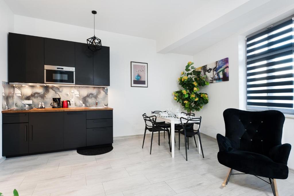 uma cozinha com armários pretos e uma mesa e cadeiras em Apartament Solny Centrum Wieliczka 11 em Wieliczka