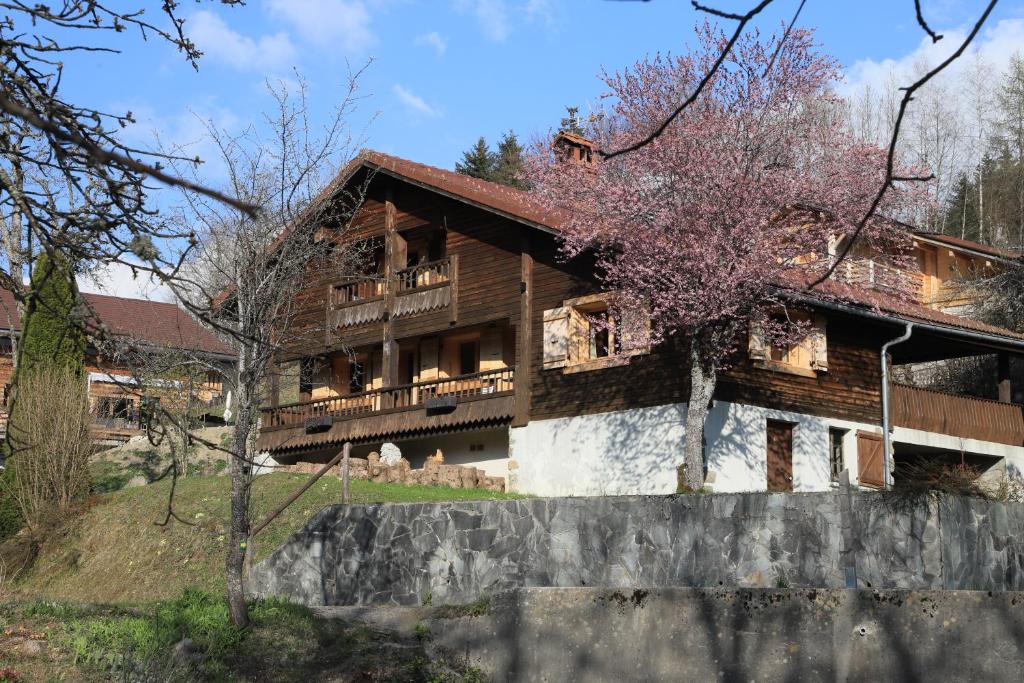 une grande maison en bois avec un balcon et un arbre dans l'établissement Sous les Ecotagnes, à Les Villards-sur-Thônes