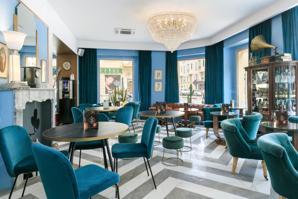 a restaurant with blue chairs and tables and a chandelier at The Jay Hotel by HappyCulture in Nice