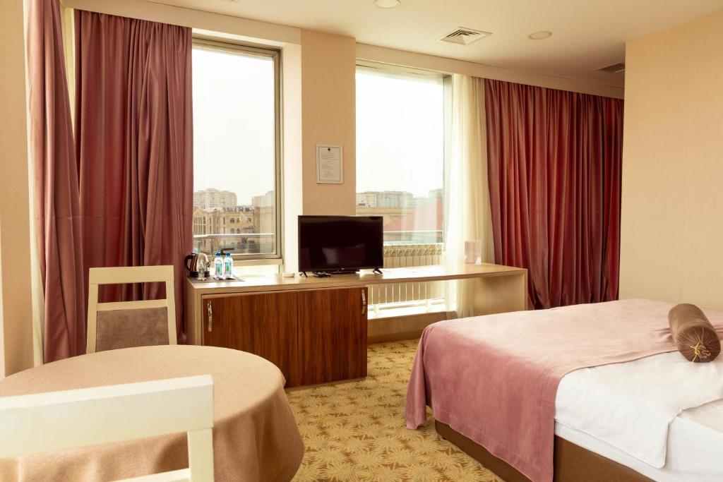 a hotel room with two beds and a flat screen tv at West Shine Hotel in Baku