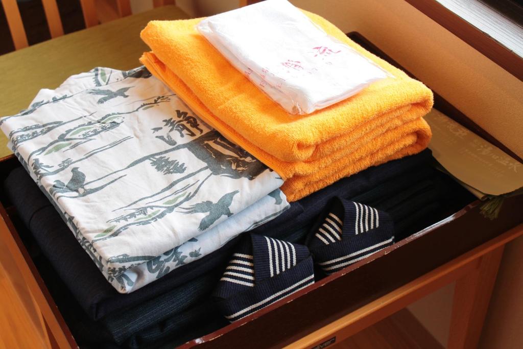 une pile de serviettes et de cravates sur une étagère dans l'établissement Iruka Onsen Hotel Seiryuusou, à Kumano 43 autres photos