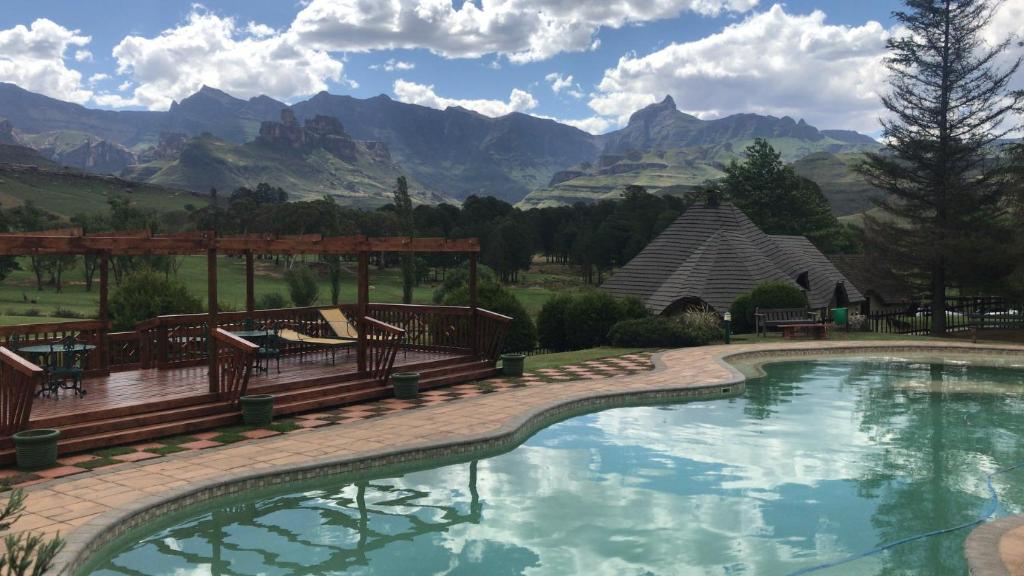 a swimming pool with benches and a view of mountains at Fairways Holiday Accommodation in Drakensberg Garden
