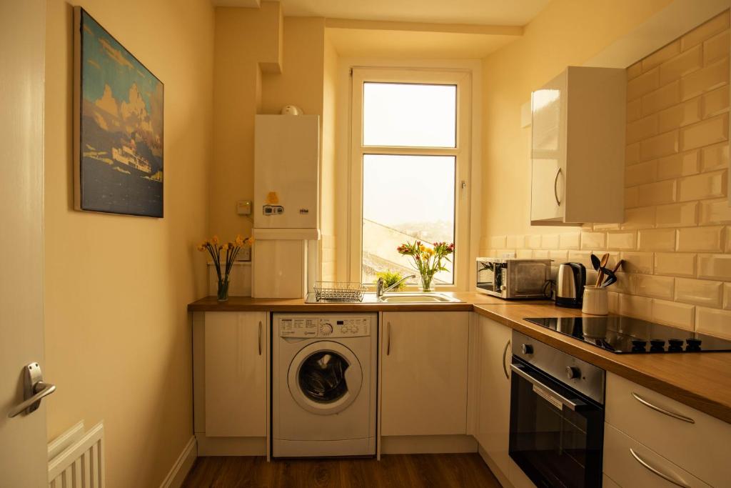 ホーイックにあるHawick Town Centre Flatのキッチン(洗濯機付)、窓が備わります。