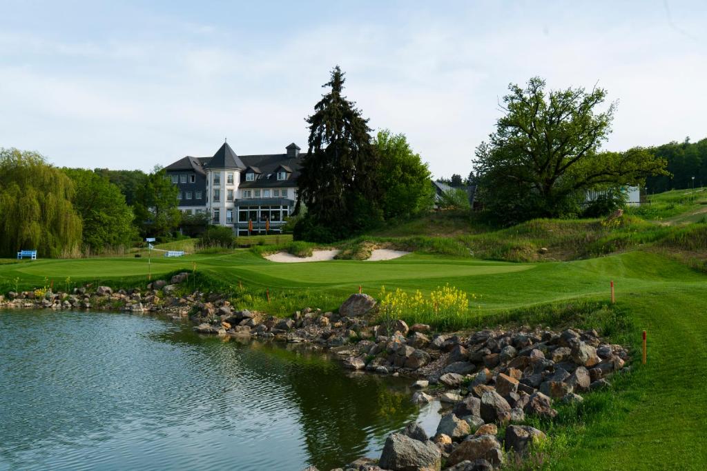 einen Golfplatz mit einem Teich vor einem Haus in der Unterkunft Hofgut Georgenthal in Burg Hohenstein