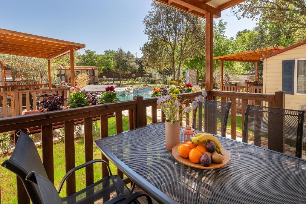 a table with a bowl of fruit on a deck at Mobile Homes Camp Green Garden Veštar in Rovinj