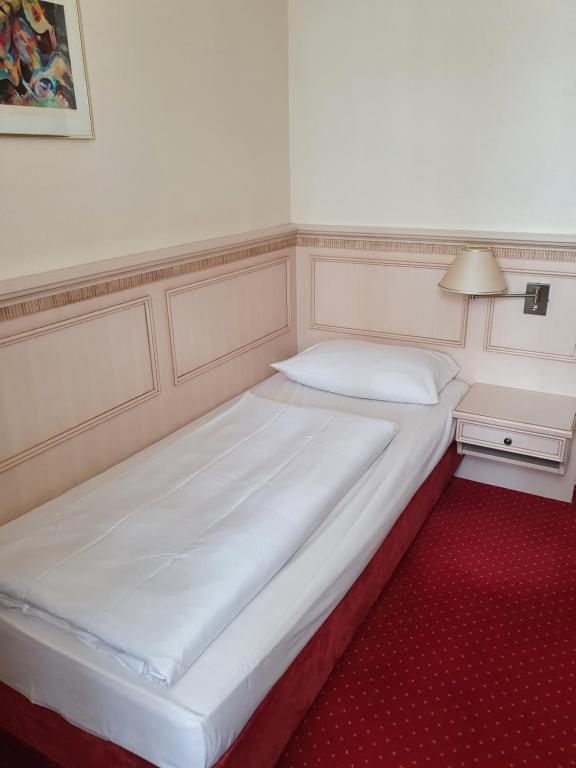 duże białe łóżko w pokoju z czerwonym dywanem w obiekcie Hotel Casino im Park w mieście Kamp-Lintfort