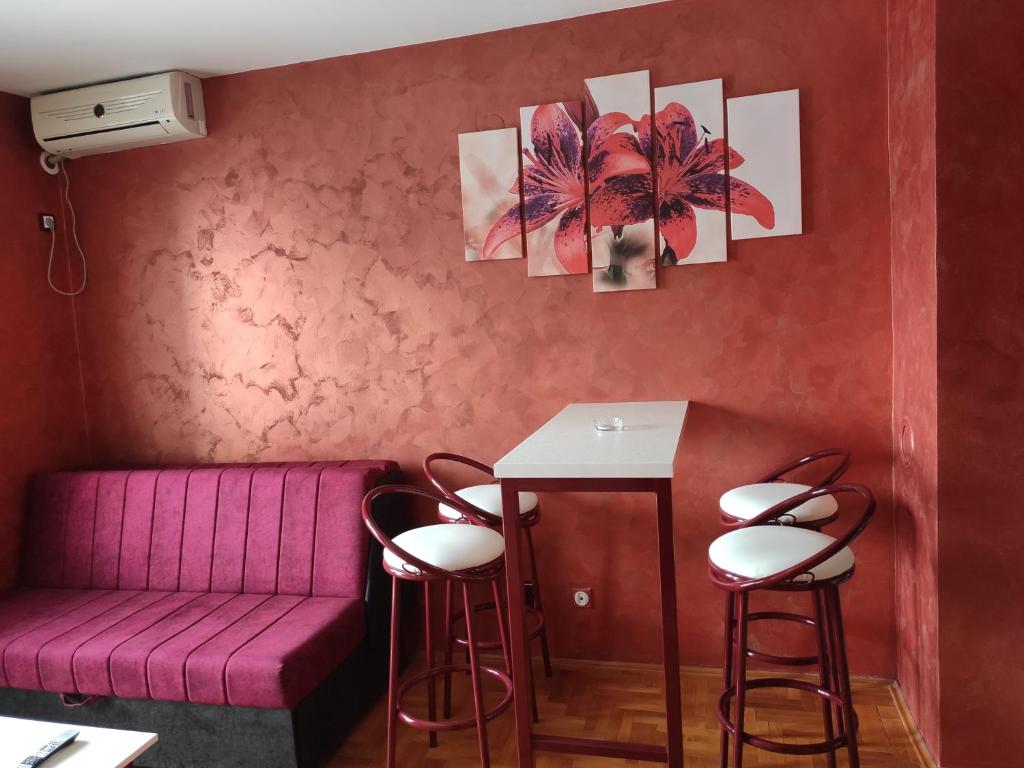 Cette chambre comprend un canapé rose, une table et des tabourets. dans l'établissement Modern cozy apartment, à Niš