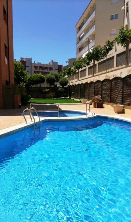 a large blue swimming pool in front of a building at SeaHomes Vacations, FENALS BEACH&CHIC, pk, top apartment full equipped in Lloret de Mar