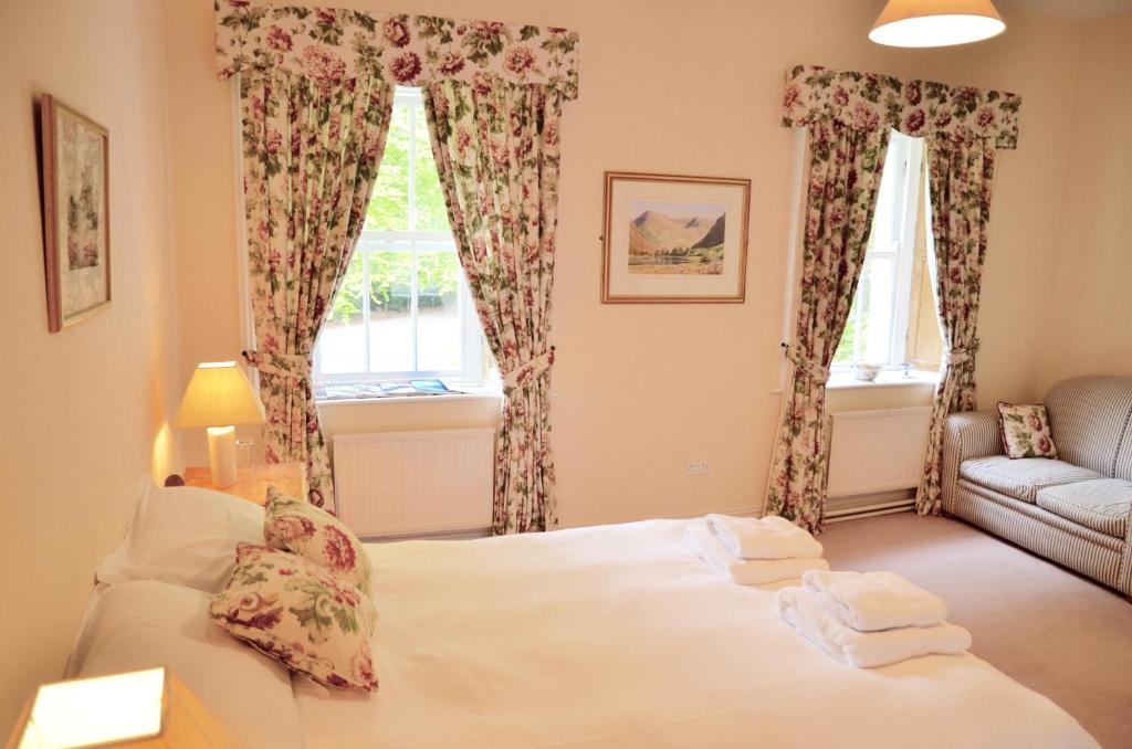 a bedroom with a bed and a couch and two windows at Delphi Lodge in Leenaun