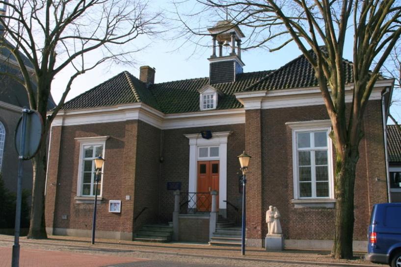 un edificio di mattoni con una statua davanti di Boetiekhotel Ons Oude Raadhuis digitaal inchecken a Hooge Zwaluwe