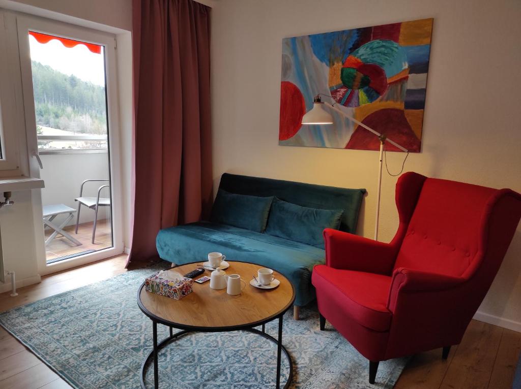 un soggiorno con divano blu e sedia rossa di Ferienwohnung Vogelnest im Schwarzwald a Baiersbronn