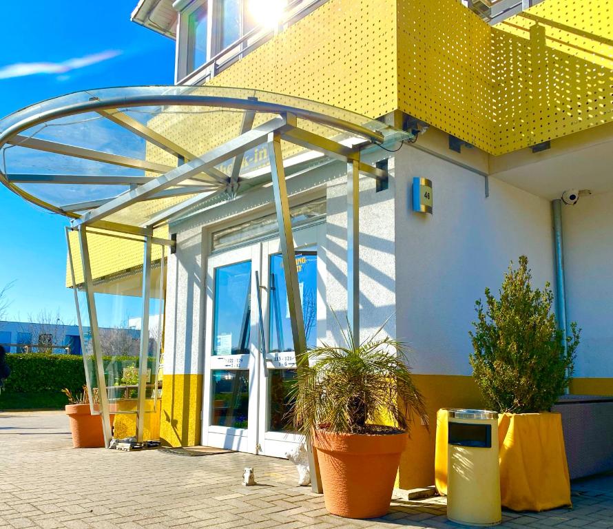 a yellow and white building with potted plants in front of it at i-Motel in Obertshausen