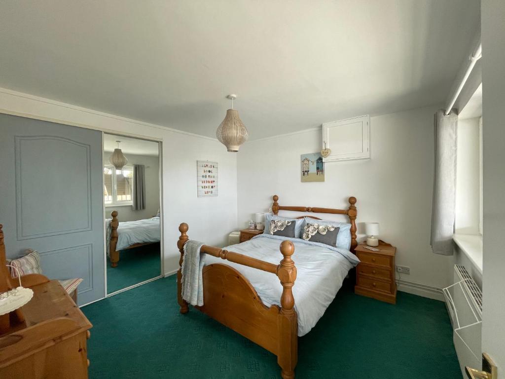 a bedroom with a wooden bed and green carpet at Barracuda, Beachside Apartment in Benllech