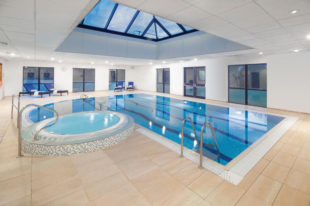 a large pool with a hot tub in a building at Holiday Inn Peterborough West by IHG in Peterborough