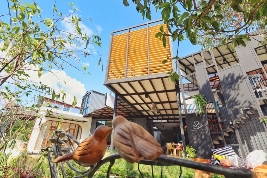 two birds sitting on a fence in front of a building at Capital O 75422 Million Pillows in Chiang Mai