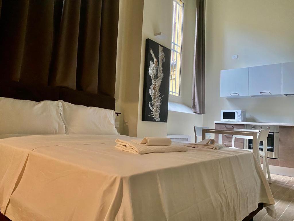 Una cama blanca con dos toallas encima. en Savenella Apartments, en Bolonia