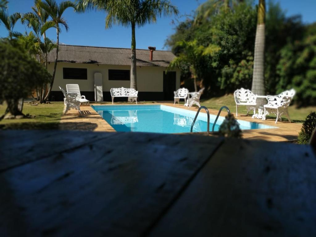 a swimming pool with chairs and a slide in front of a house at Pousada O Caipira in Pouso Alto