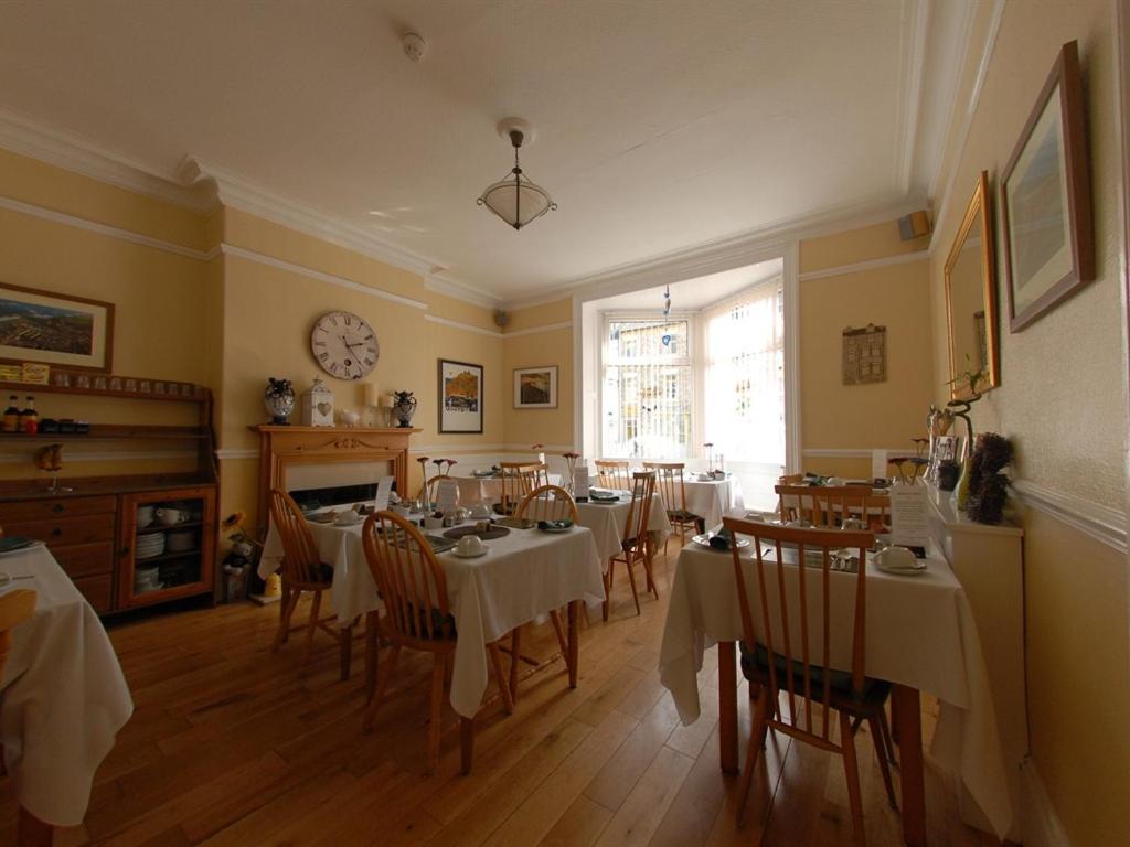 a dining room with tables and chairs and a clock on the wall at Chiltern Guest House in Whitby