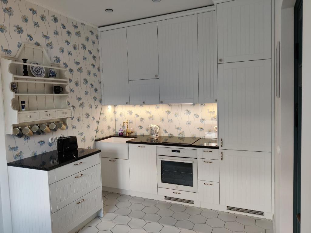 a white kitchen with white cabinets and appliances at Esplanaadi Luxury Apartment in Pärnu