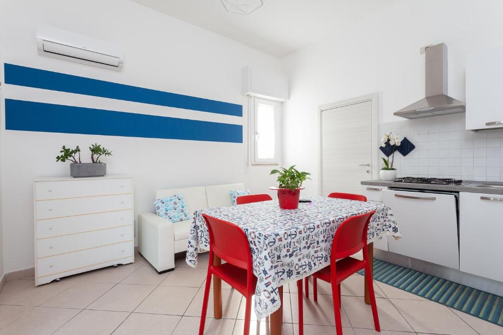 une cuisine avec une table avec des chaises rouges et un bleu dans l'établissement Nicola House Il Faro, à Cervia